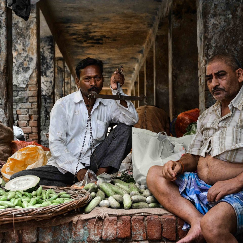 Due uomini vendono ortaggi al mercato di Varanasi in India